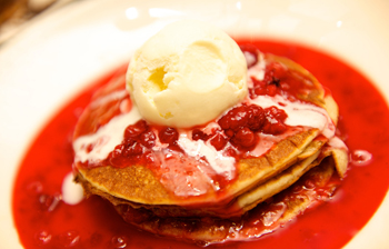 A pancake topped with berries and ice cream