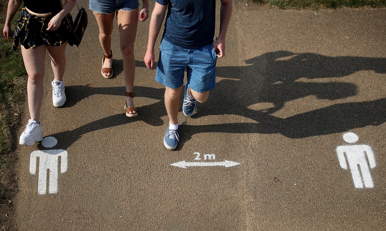 Young people walk across physical distancing marks on pavement