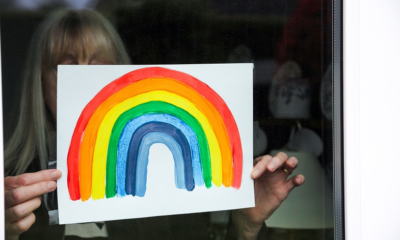 Woman puts rainbow painting in window
