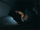 A woman looking at social media on her phone late at night in bed