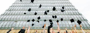 Graduates throwing hats outside Arts Tower