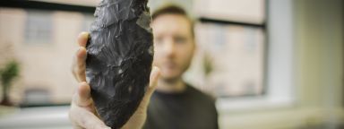 Archaeology student holding up archaeological find