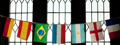 A line of different countries' flags hung up in front of a window