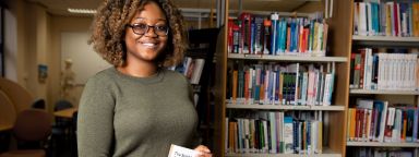 A female student in the School of Health and Related Research library with a book.