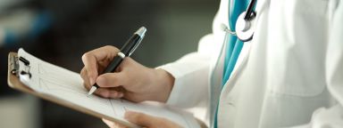 A photo showing a doctor writing on a clipboard