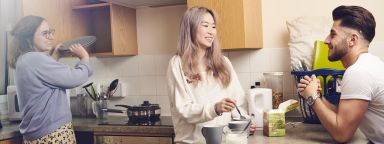 photo of students in kitchen, drinking tea and putting plates into a cupboard