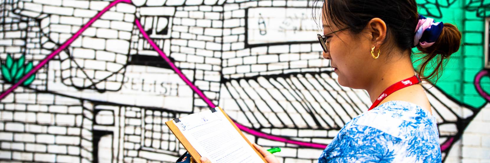 Student making notes in front of colourful street art