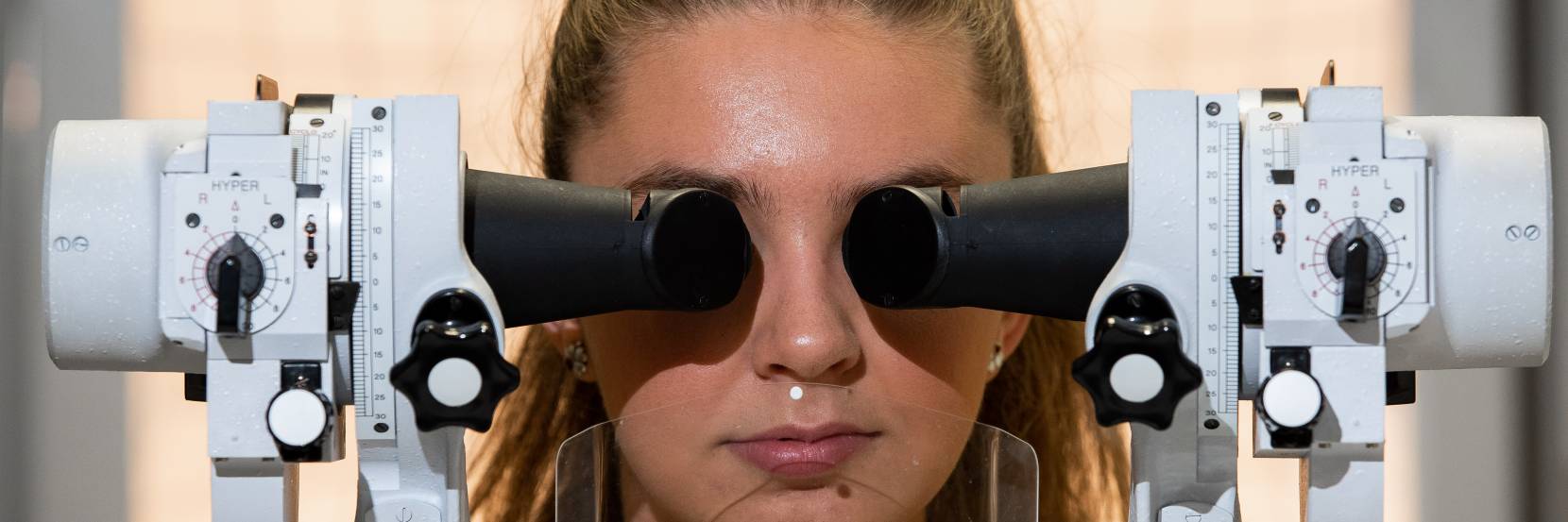 Female student sat in front of eye testing equipment
