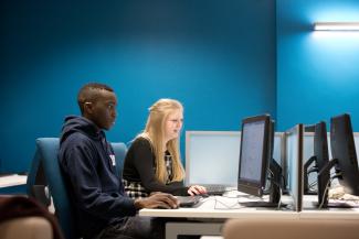 Image of two postgraduate law students on computer with blue background