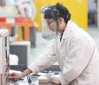Image of postgraduate materials science and engineering student using equipment with mask