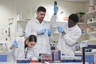 Group of three postgraduate students in the medical scool using medical equipment