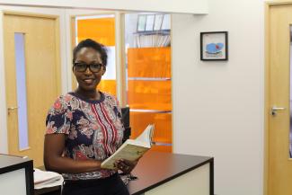 Postgraduate politics student, Winfred Syombua holding a book