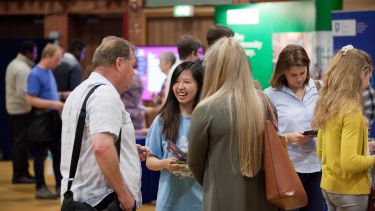 Prospective students talking to staff at the open day central exhibition