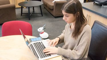 Student on laptop with phone
