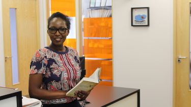 Postgraduate politics student, Winfred Syombua holding a book