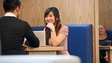 Student with laptop talking to colleague