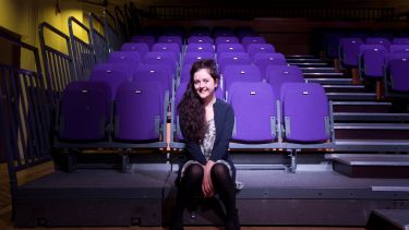 Helen Monks poses for the camera in a theatre.