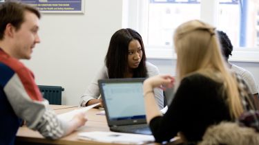 Students gather around a table.