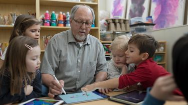 Man teaching children with tablet