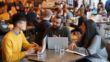 Group of students working on laptops in a cafe