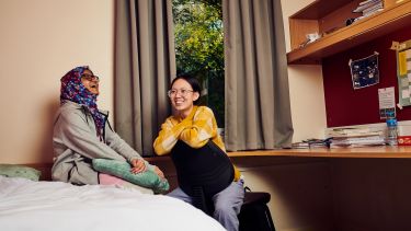 Two students laughing in a bedroom