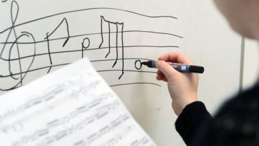 A research student writing musical notation on a whiteboard