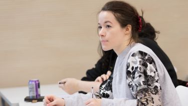 DLL mature student taking notes in a seminar 