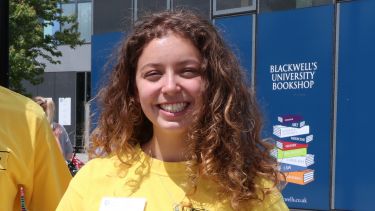 Hannah Dibble, English and History student, smiling at camera stood outside Blackwell's bookshop 