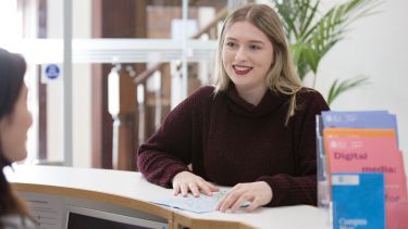 Student stood at the enquiry desk in Elmfield