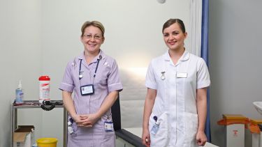 Two nurses smile for the camera. 