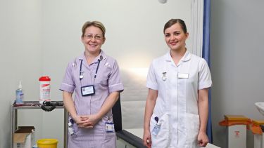 Two nurses smile for the camera.