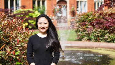 A chinese student infront of the fountains in Firth Court