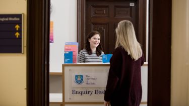 A student stood at the enquiry desk in the Elmfield Building