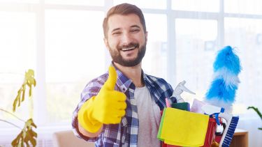 A man smiling holding cleaning equipment 