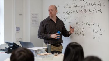 An academic member of staff delivering a seminar and using a whiteboard - image