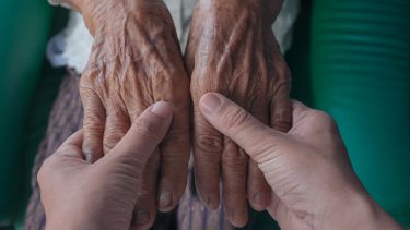 A photograph of an elderly person's hands being massaged by a younger person.