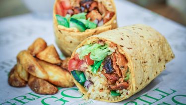 A picture of a burrito with potato wedges on the side 