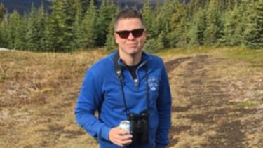 Dr Paul Morris with binoculars and a can of juice out walking.