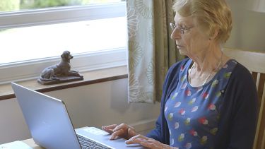 An elderly patient uses a laptop to check the online Joint Risk Calculator