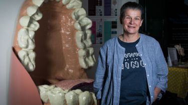 Professor Fiona Boissonade standing next to a giant model of gums and teeth. 
