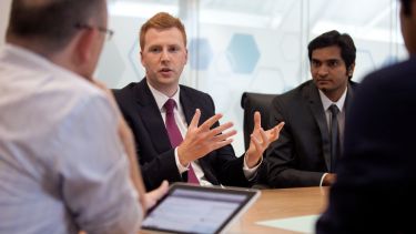 Four men in a meeting around a table sharing ideas
