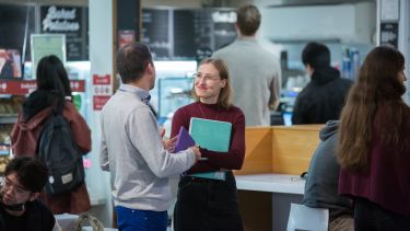 Two students talking in the courtyard café