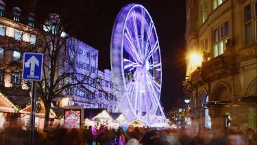 Christmas Lights Switch On at Sheffield city hall. A spinning ferris wheel, brightly lit at night.