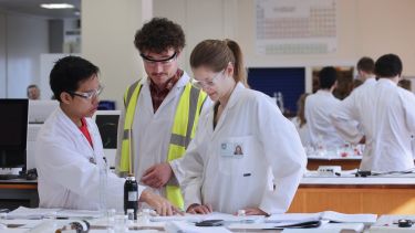 Three students gathered around working on an experiment 
