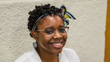 Student in white shirt and glasses sat and looking into camera