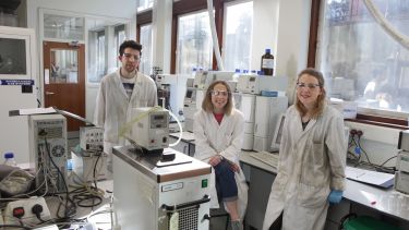 Three students in the lab face the camera