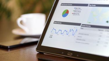 stats displayed on a tablet with a phone and cup