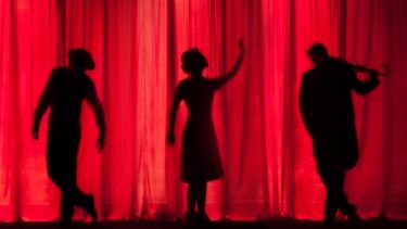 Silhouettes of three performers on a stage.