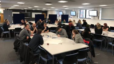 A group of technicians from the University of Sheffield share ideas at a seminar table.
