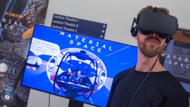 Man wearing virtual reality headset in front of an electronic display